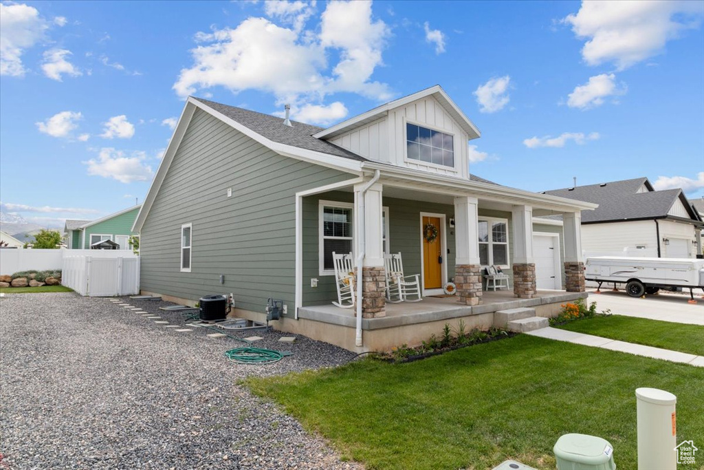 View of front of house with covered porch, board and batten siding, a garage, and central AC unit