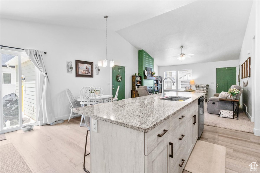 Kitchen with a sink, open floor plan, stainless steel dishwasher, light wood finished floors, and an island with sink