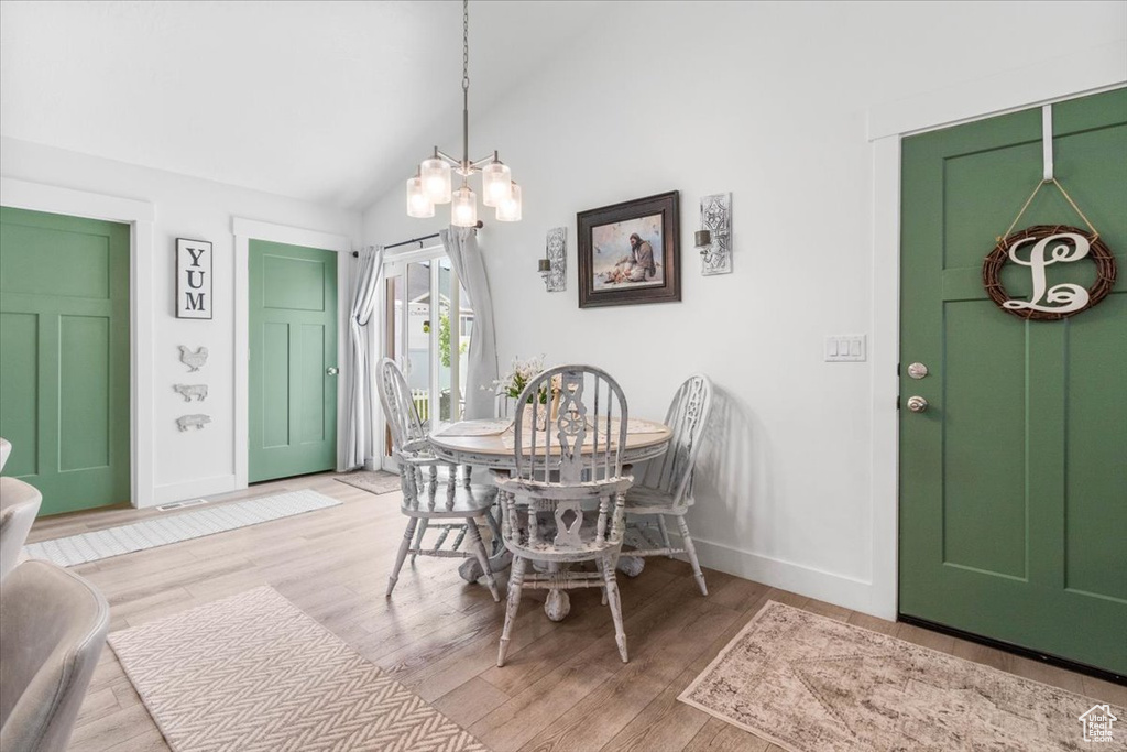 Dining room with baseboards, light wood-style flooring, lofted ceiling, and a chandelier
