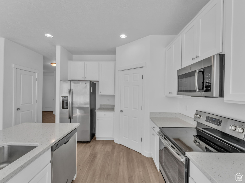 Kitchen featuring stainless steel appliances, white cabinetry, and recessed lighting