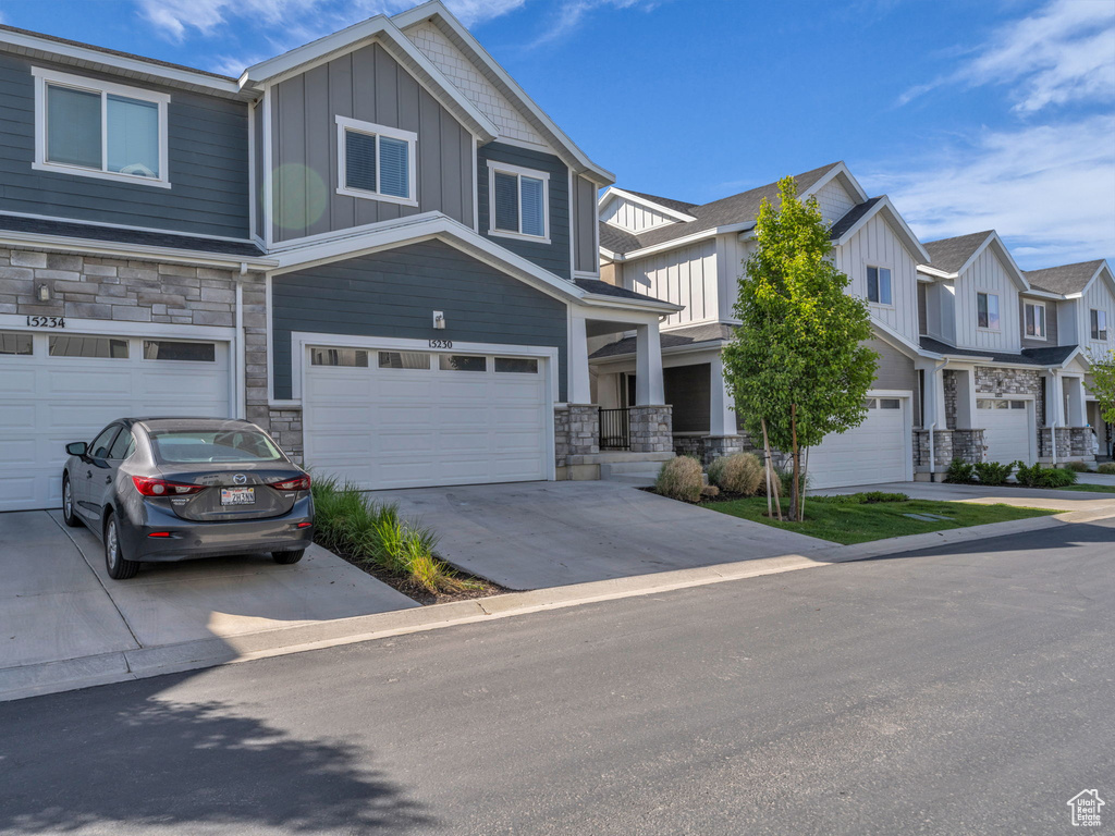 View of front of home featuring stone siding, board and batten siding, an attached garage, and driveway