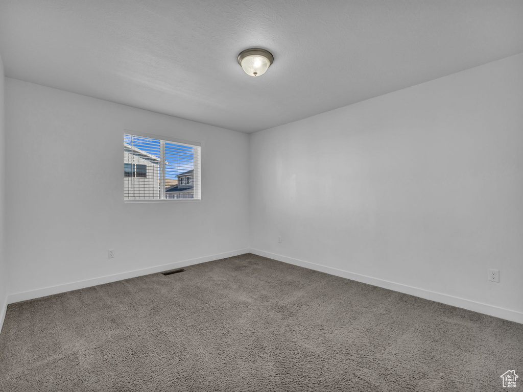 Empty room with baseboards and dark colored carpet