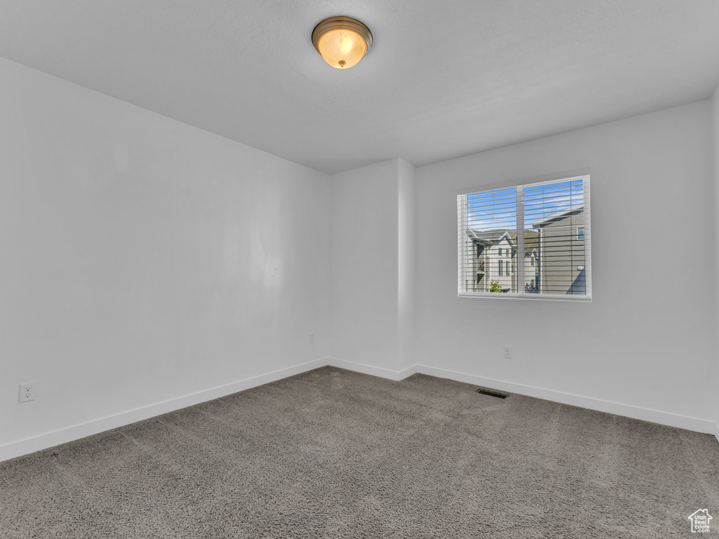 Spare room featuring baseboards and dark colored carpet