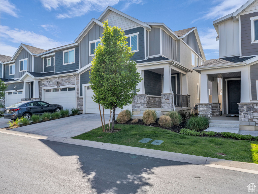 Craftsman-style house with board and batten siding, a garage, stone siding, and driveway