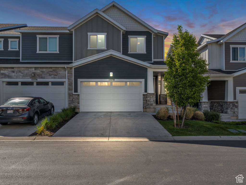 View of front of property featuring stone siding, an attached garage, board and batten siding, and concrete driveway