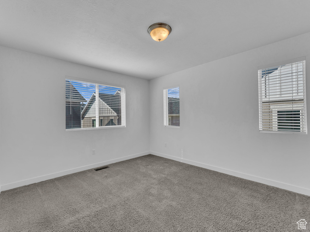 Unfurnished room with baseboards and healthy amount of natural light