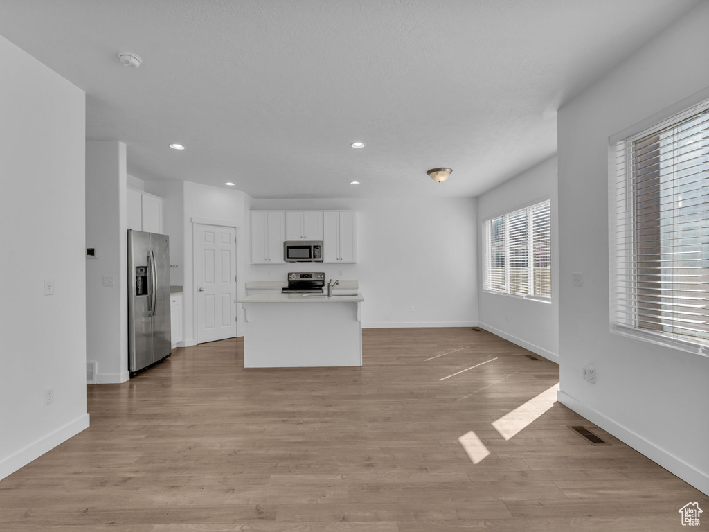 Kitchen featuring stainless steel appliances, white cabinetry, recessed lighting, baseboards, and open floor plan
