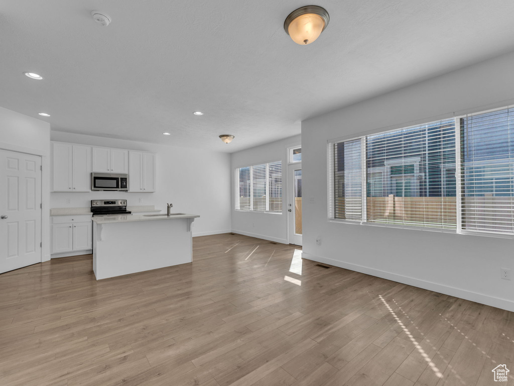 Kitchen with appliances with stainless steel finishes, baseboards, a sink, recessed lighting, and white cabinets