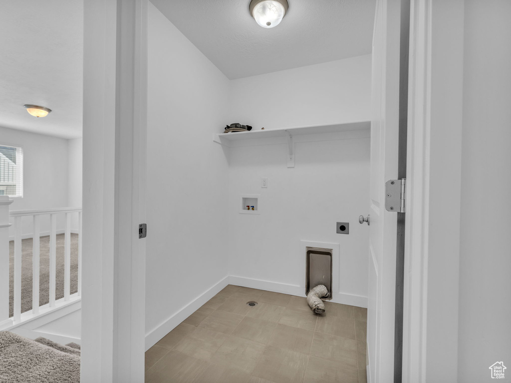 Clothes washing area with electric dryer hookup, washer hookup, and baseboards