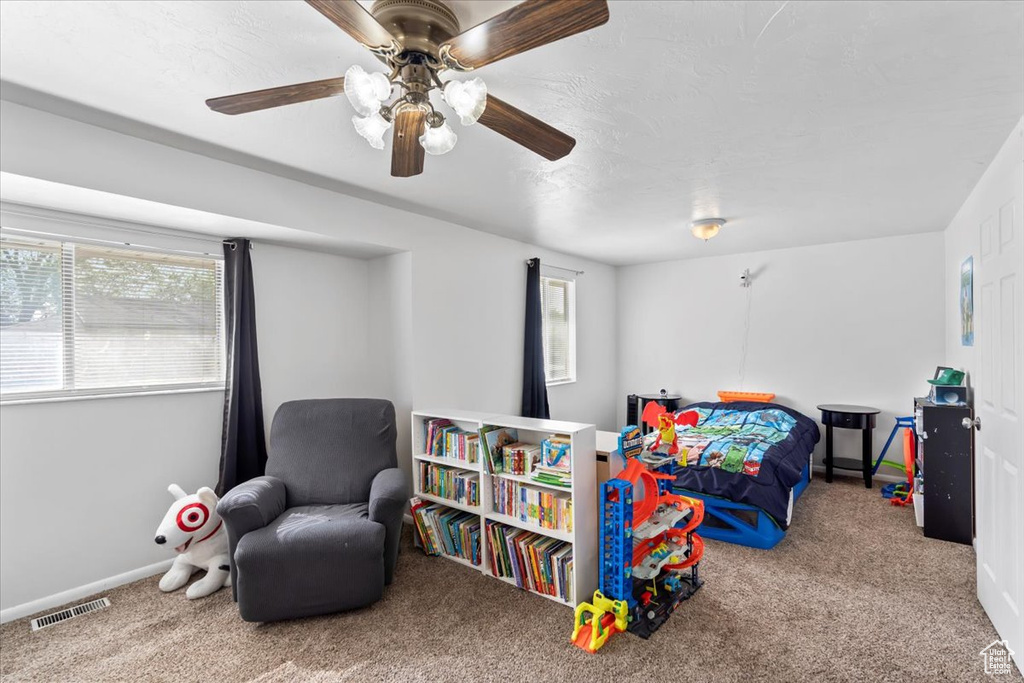 Carpeted bedroom with a ceiling fan and baseboards
