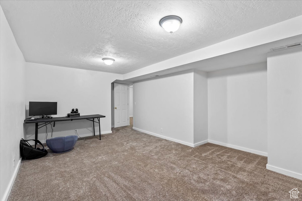 Finished basement with a textured ceiling, carpet floors, and baseboards