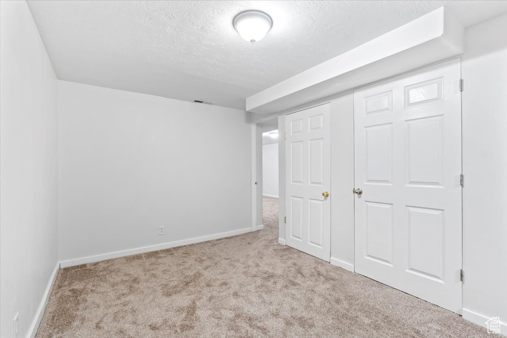 Unfurnished bedroom with carpet, a textured ceiling, baseboards, and a closet