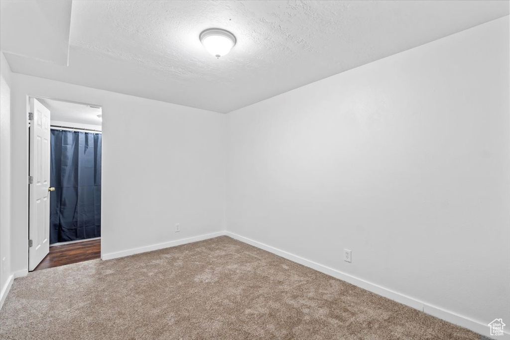 Carpeted spare room featuring baseboards and a textured ceiling