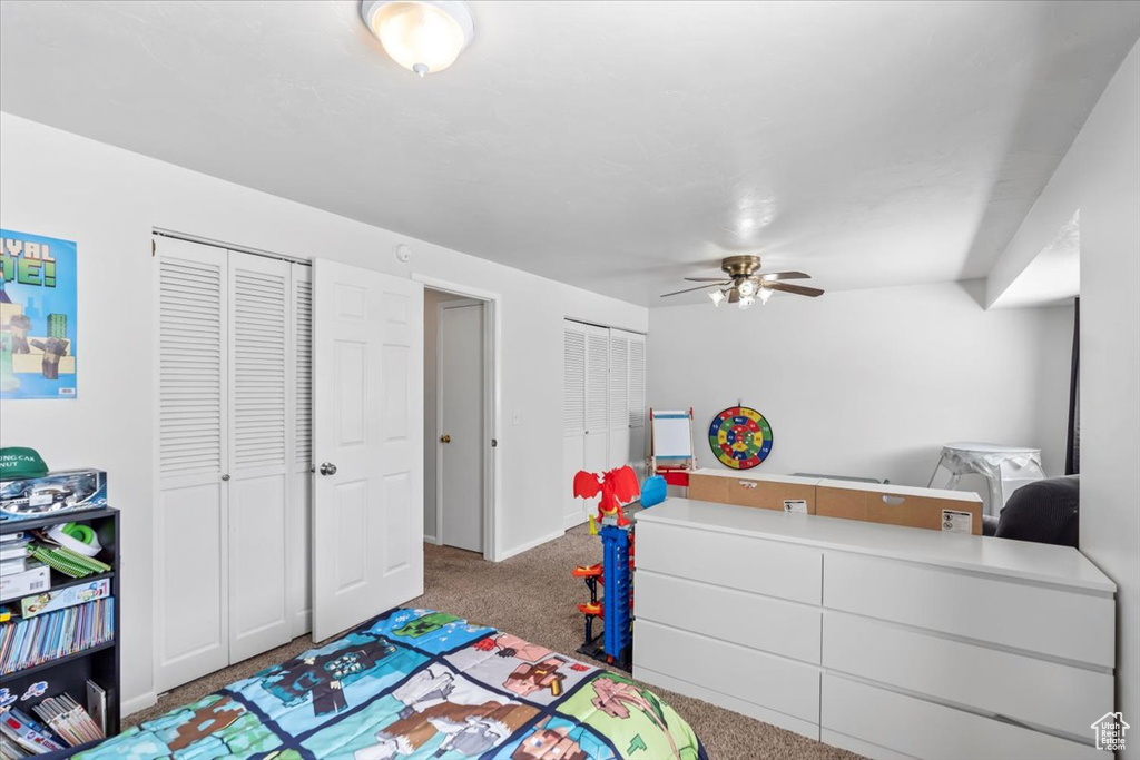 Bedroom with multiple closets, carpet flooring, baseboards, and ceiling fan