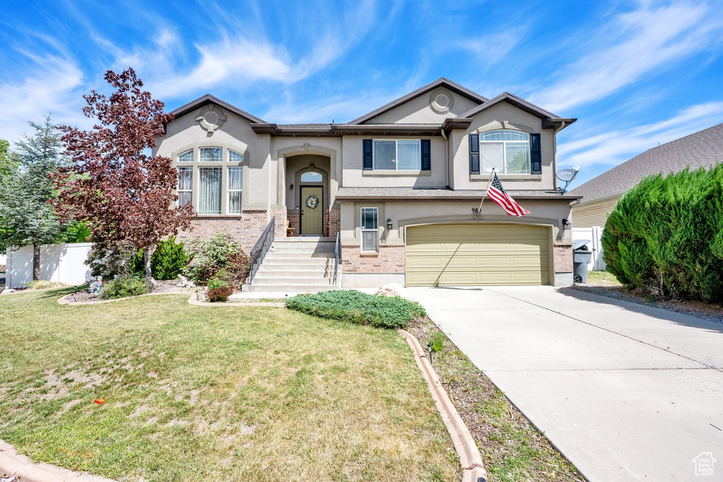 View of front of house with stucco siding, an attached garage, driveway, and a front lawn