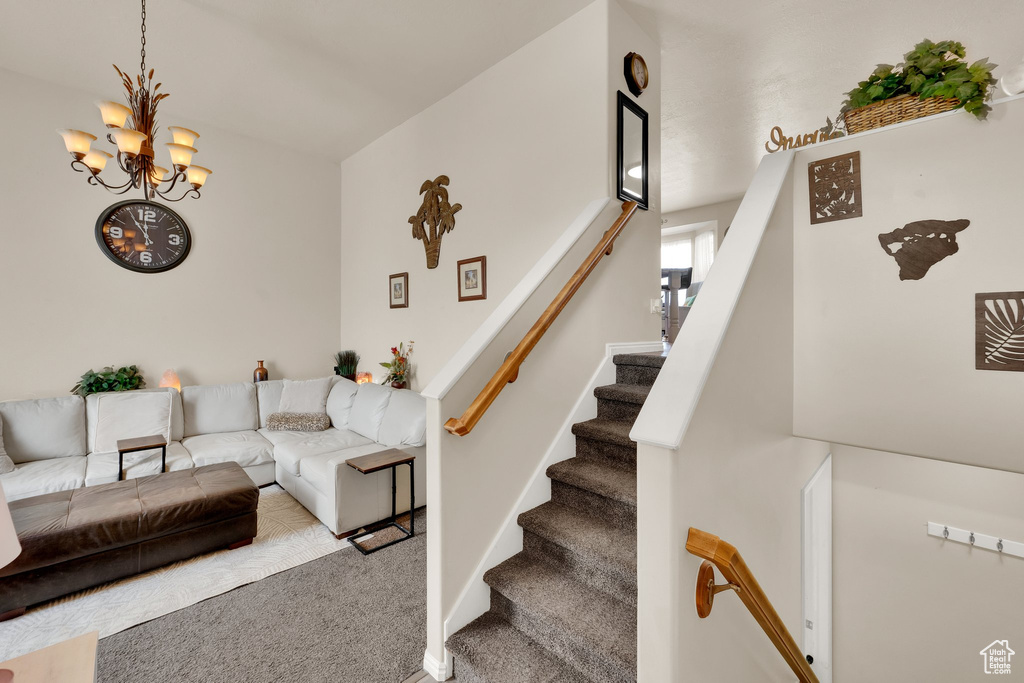 Living room with a chandelier, carpet, and stairs