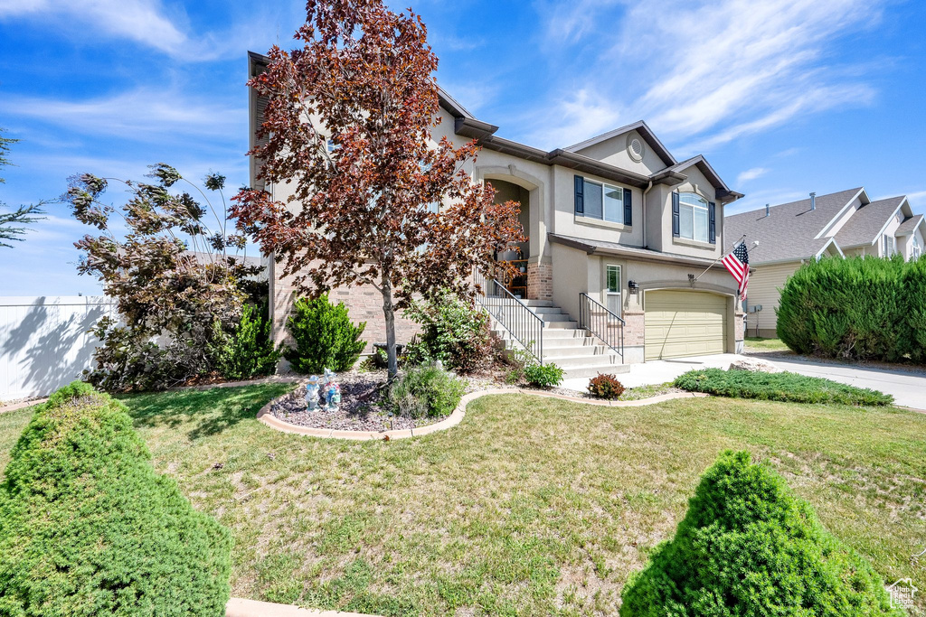 View of front facade featuring stucco siding, concrete driveway, a garage, and a front yard