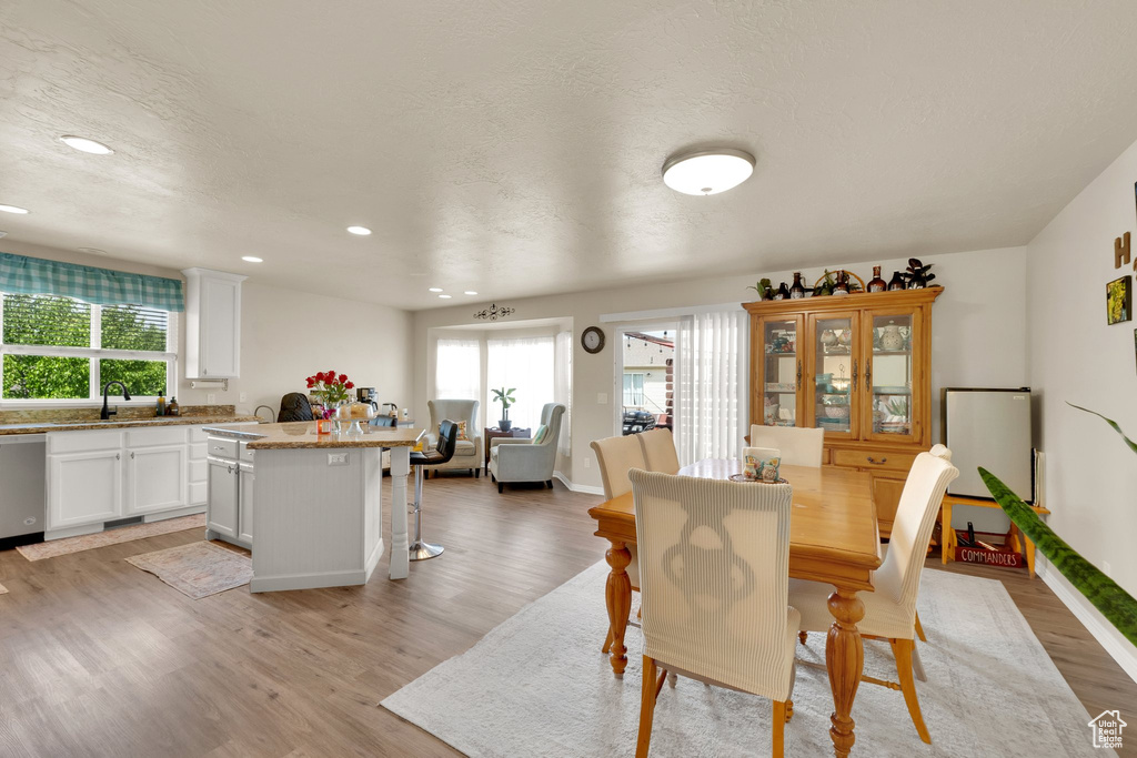 Dining room featuring light wood-type flooring, plenty of natural light, recessed lighting, a textured ceiling, and baseboards