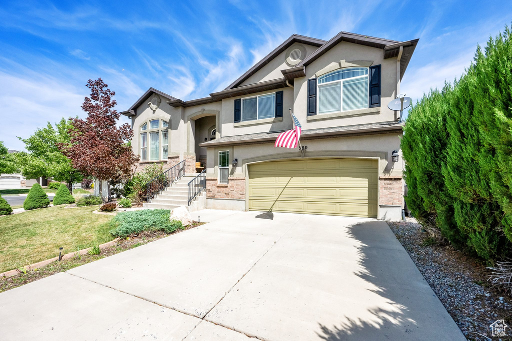 View of front of house with stucco siding, a garage, concrete driveway, and a front yard