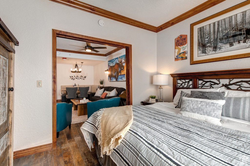 Bedroom with ornamental molding, wood-type flooring, baseboards, and a chandelier