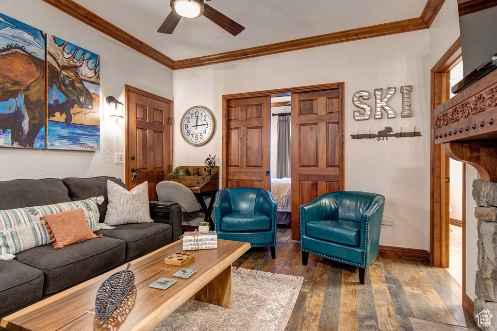 Living room featuring hardwood / wood-style floors, ornamental molding, ceiling fan, and baseboards