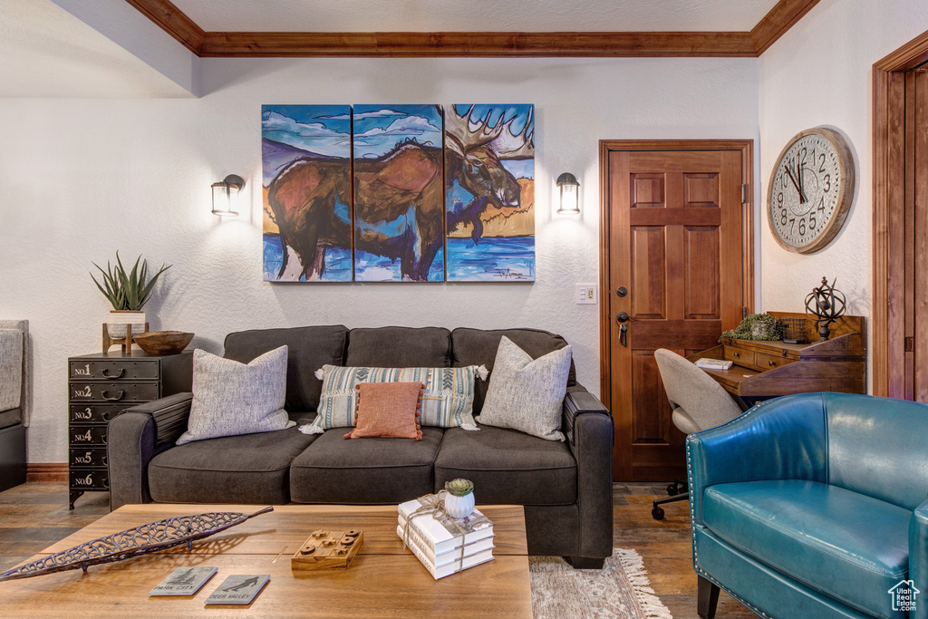 Living room with wood finished floors, ornamental molding, and baseboards