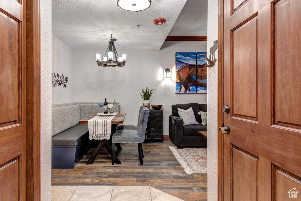 Dining space featuring wood finished floors, a chandelier, breakfast area, a textured wall, and a textured ceiling