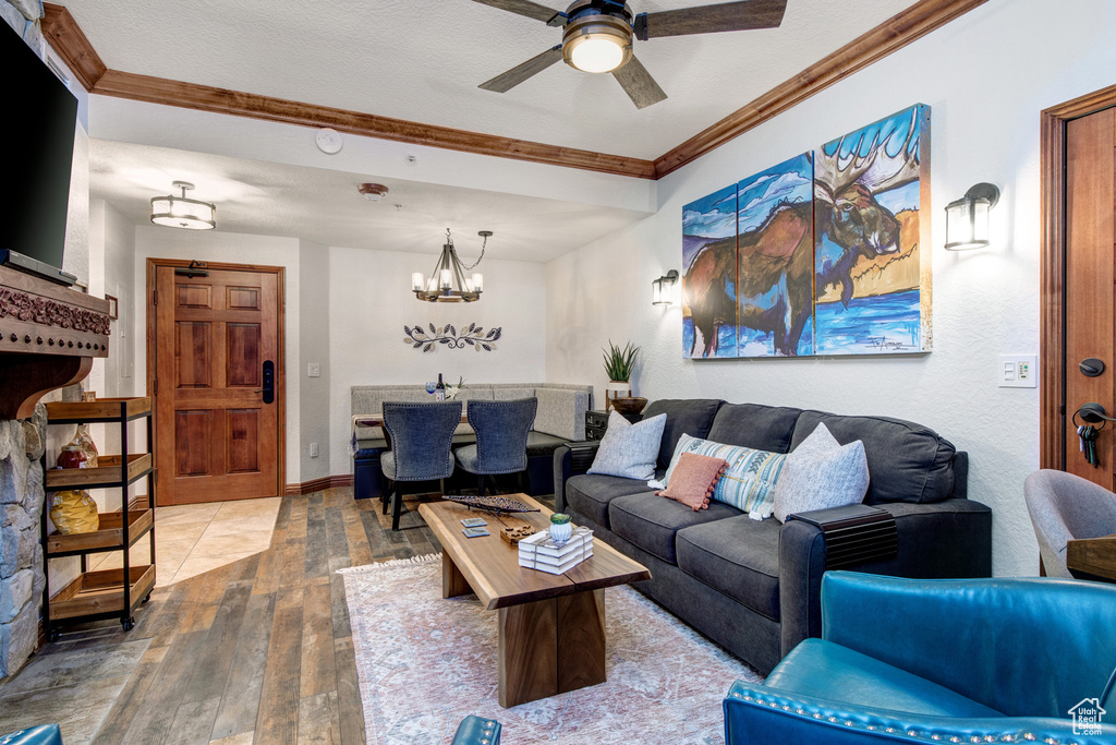 Living area with hardwood / wood-style flooring, ornamental molding, a chandelier, ceiling fan, and baseboards