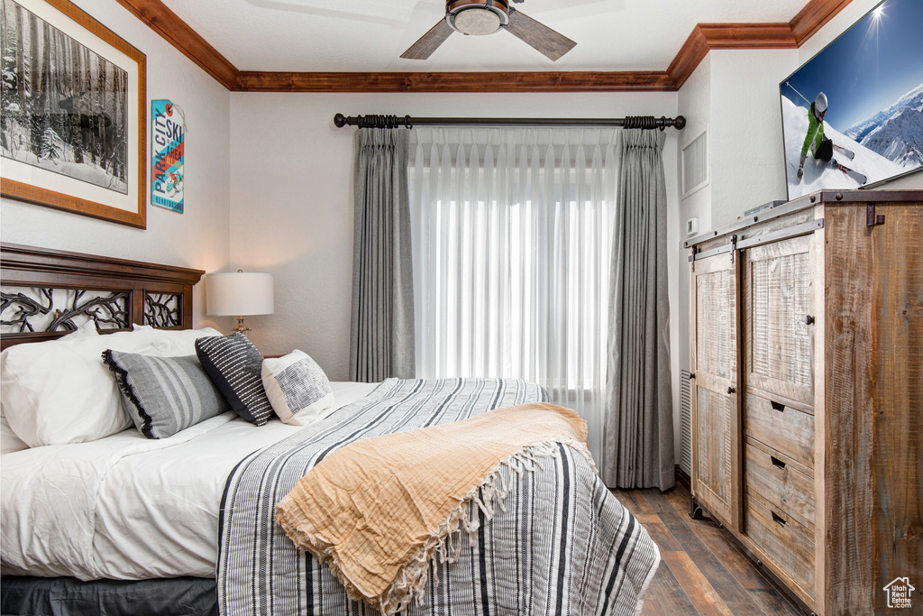 Bedroom with ornamental molding, dark wood finished floors, and a ceiling fan