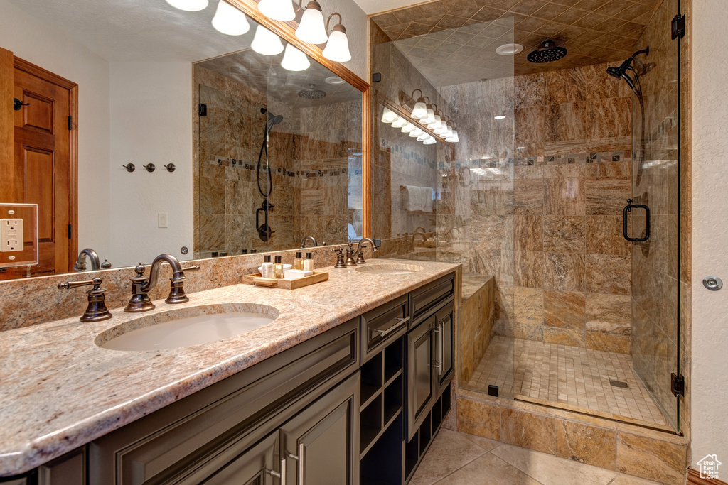 Bathroom with a stall shower, double vanity, and tile patterned floors