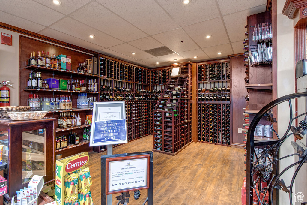 Wine cellar with a paneled ceiling, wood finished floors, and recessed lighting