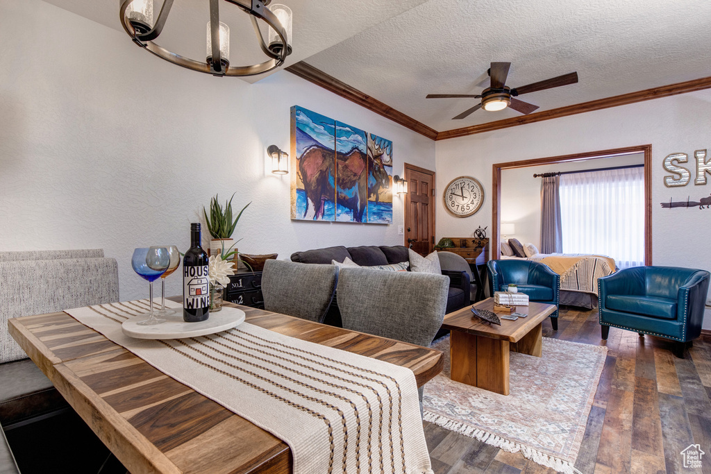 Dining area featuring wood-type flooring, a chandelier, ceiling fan, a textured ceiling, and crown molding