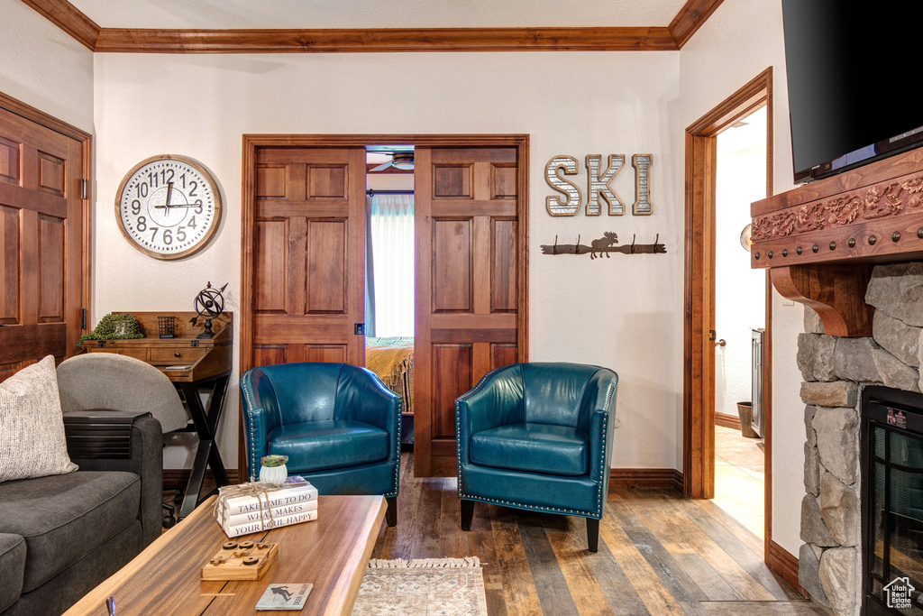 Living room featuring ornamental molding, wood finished floors, a fireplace, ceiling fan, and baseboards