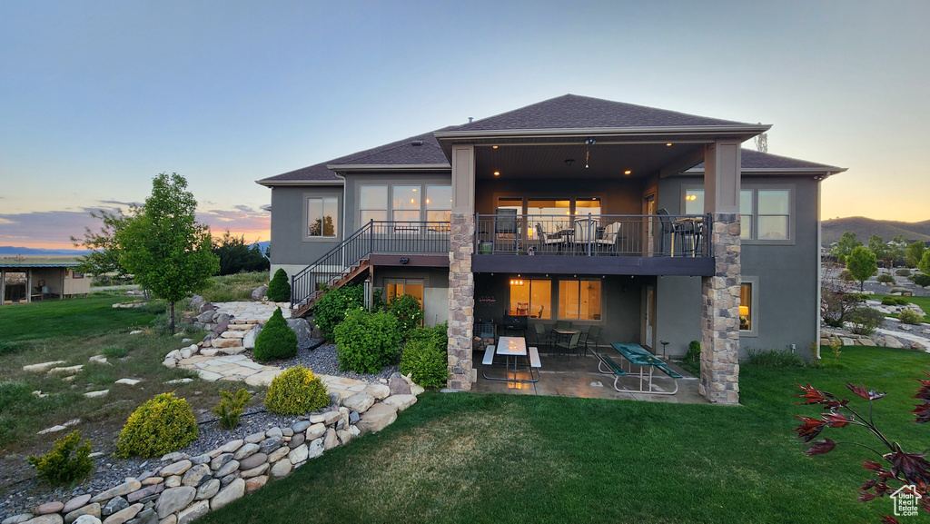 Back of property with a patio, stucco siding, stairs, and a lawn