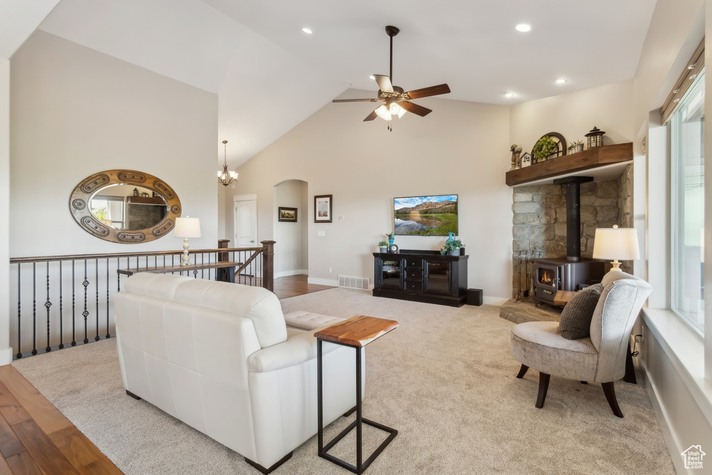 Living room featuring a ceiling fan, arched walkways, a wood stove, high vaulted ceiling, and recessed lighting