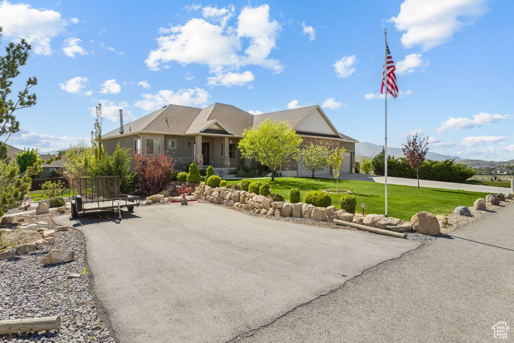 View of front of property with a front yard and curved driveway