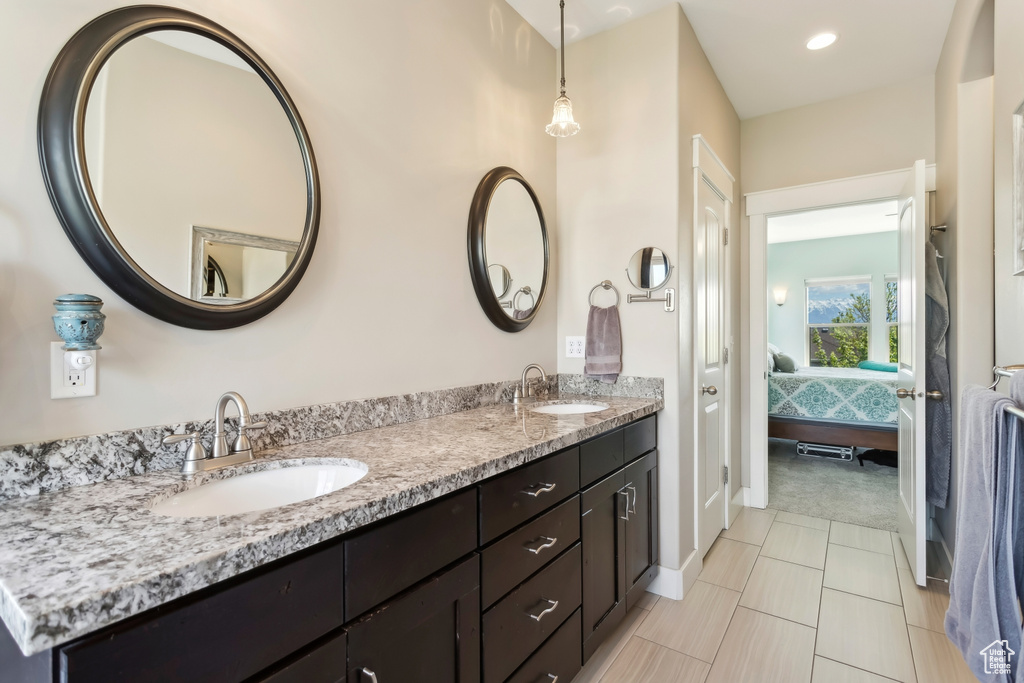Ensuite bathroom with double vanity, baseboards, and tile patterned flooring