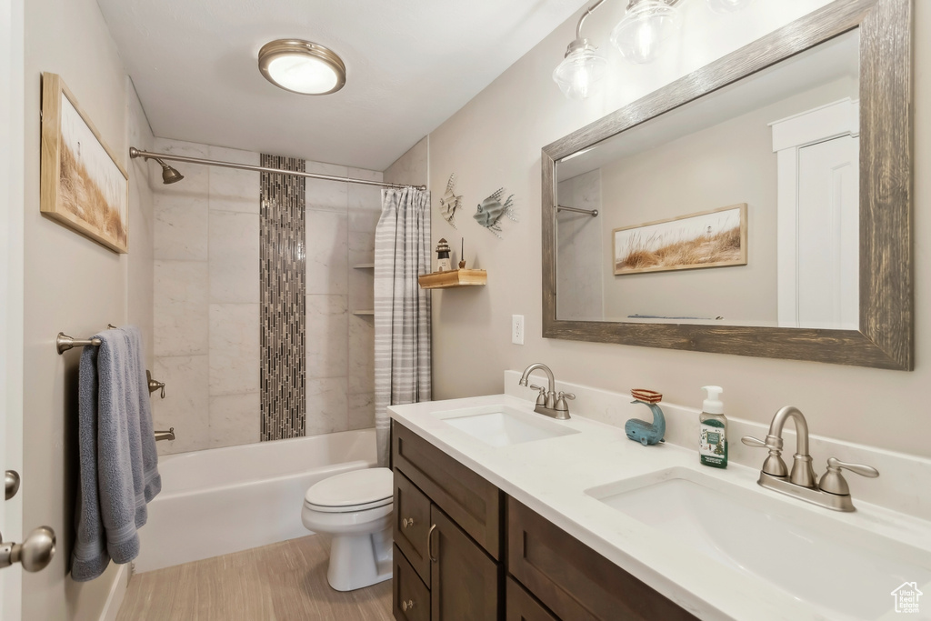 Full bath featuring toilet, shower / tub combo with curtain, and double vanity