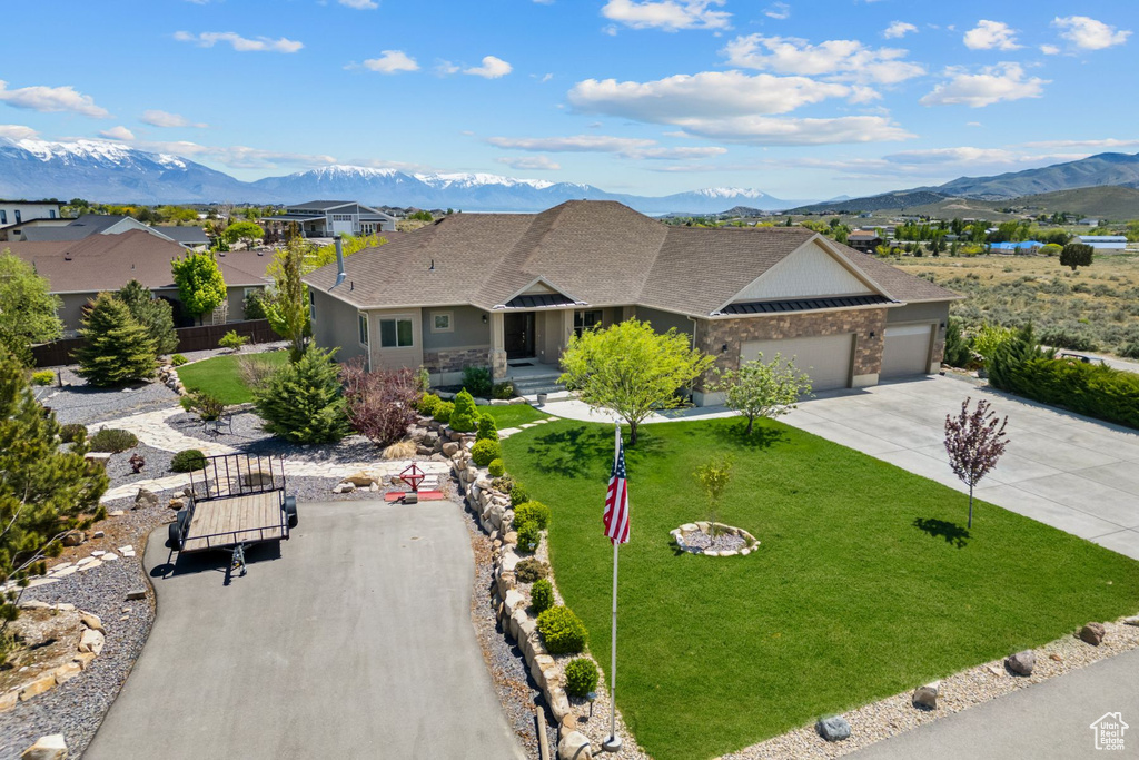 Ranch-style house featuring a garage, a mountain view, driveway, and roof with shingles