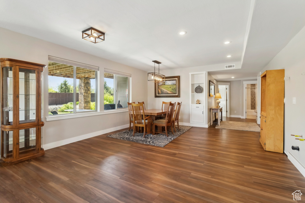 Dining space featuring baseboards, wood finished floors, built in shelves, recessed lighting, and a chandelier