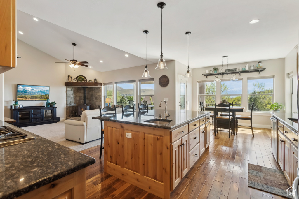Kitchen with a sink, hardwood / wood-style flooring, a wood stove, dark stone counters, and recessed lighting