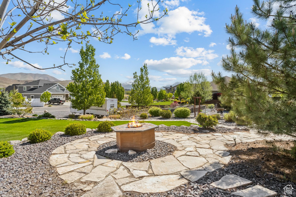 View of green lawn featuring an outdoor fire pit and a mountain view