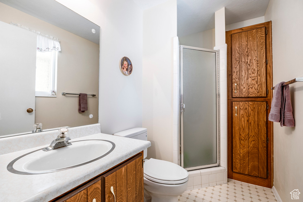 Bathroom featuring toilet, a shower stall, and vanity