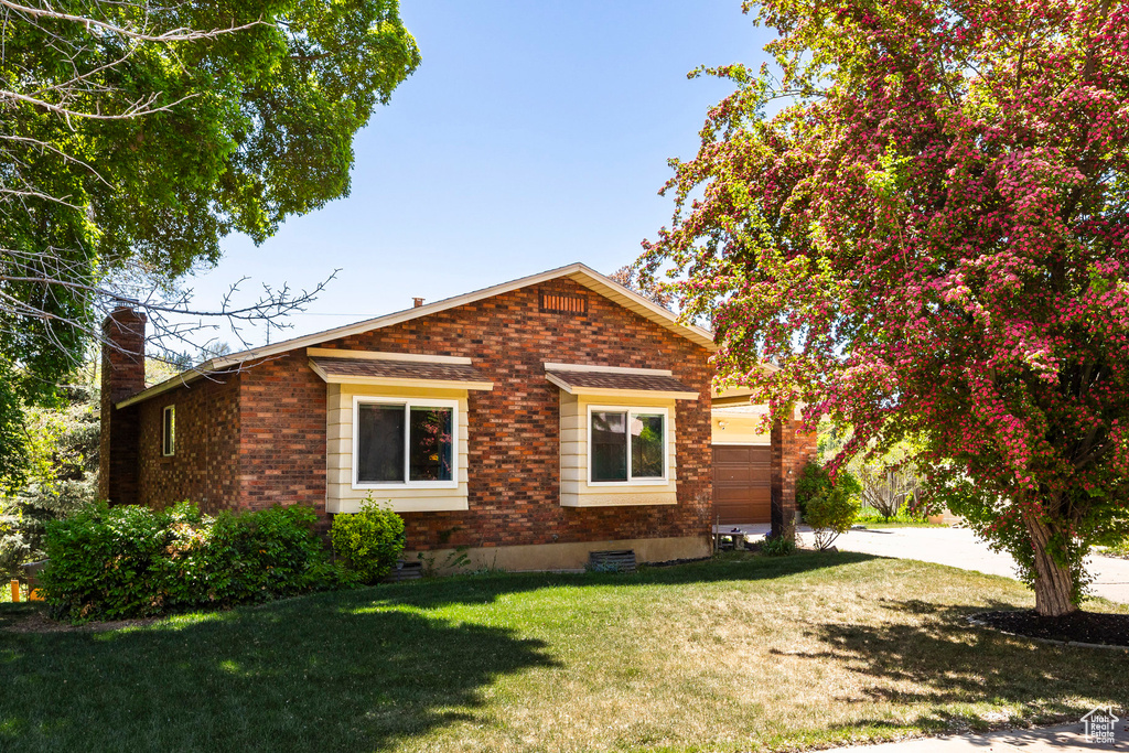 View of home's exterior featuring brick siding, a chimney, and a lawn