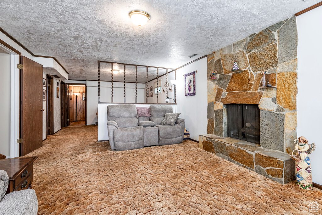 Carpeted living room with a textured ceiling and a stone fireplace