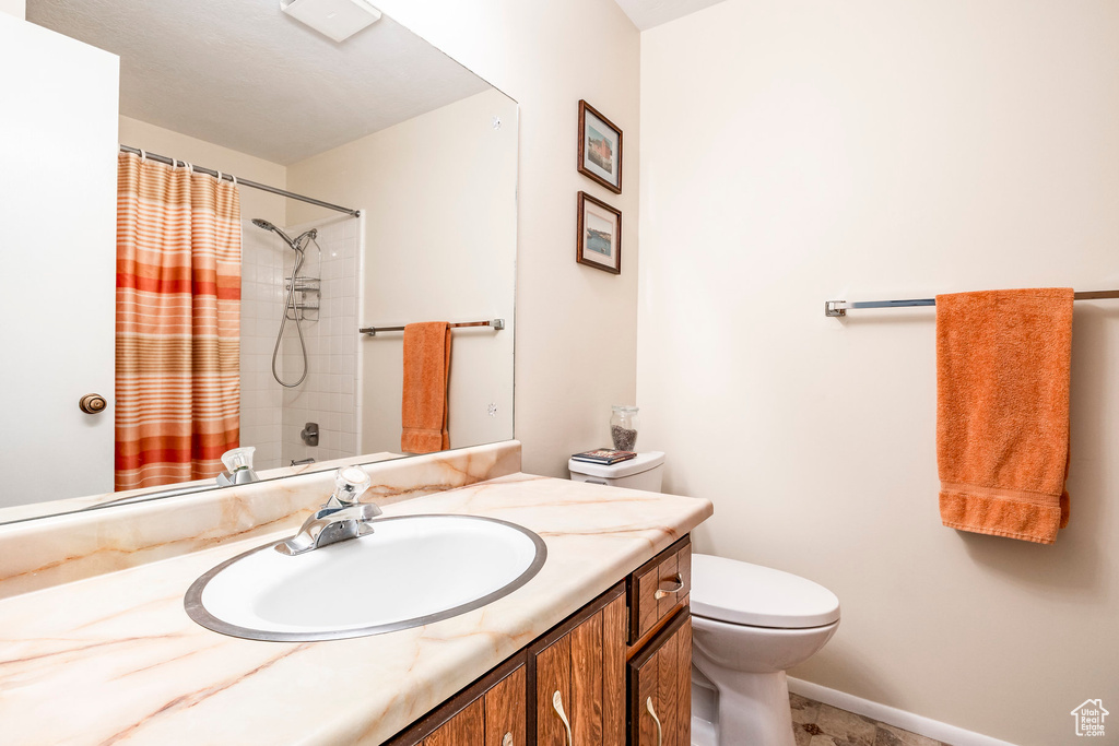 Bathroom with toilet, a shower with curtain, vanity, and baseboards
