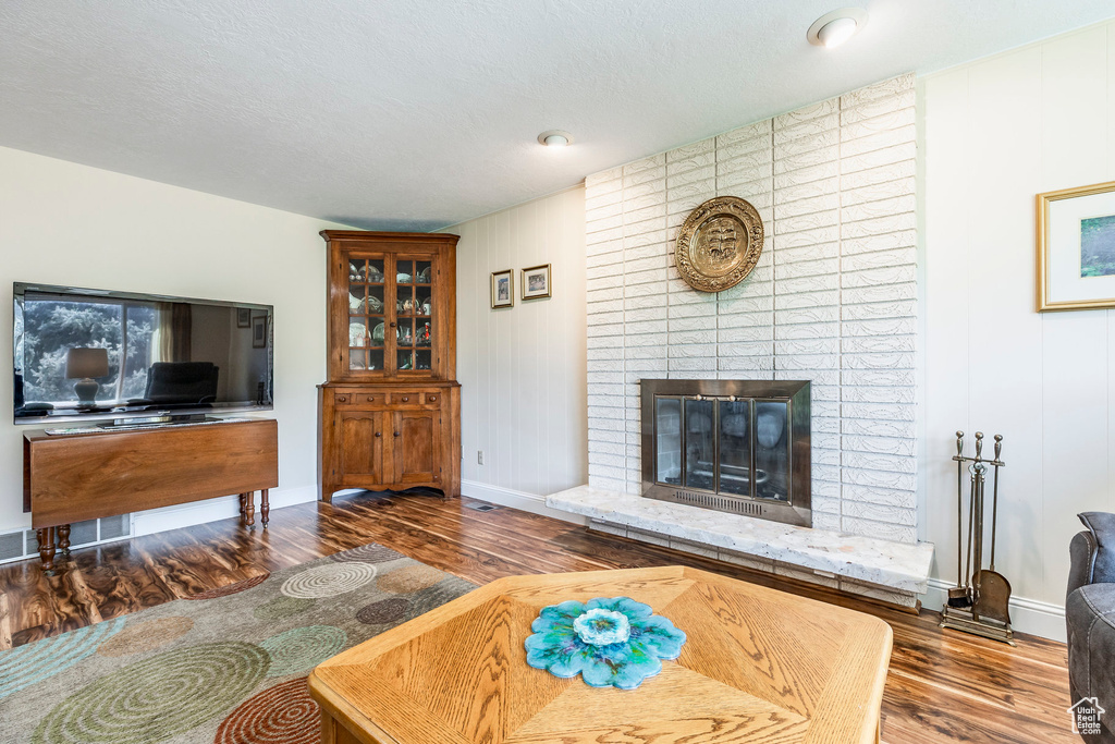Living area featuring wood finished floors, a brick fireplace, and baseboards