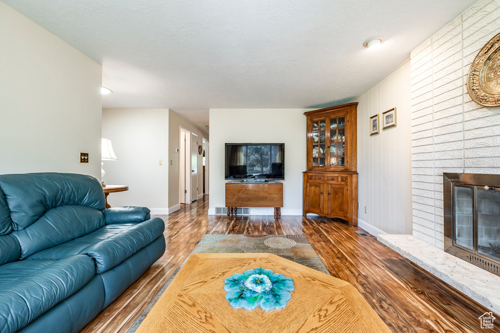 Living room with wood finished floors, baseboards, and a fireplace
