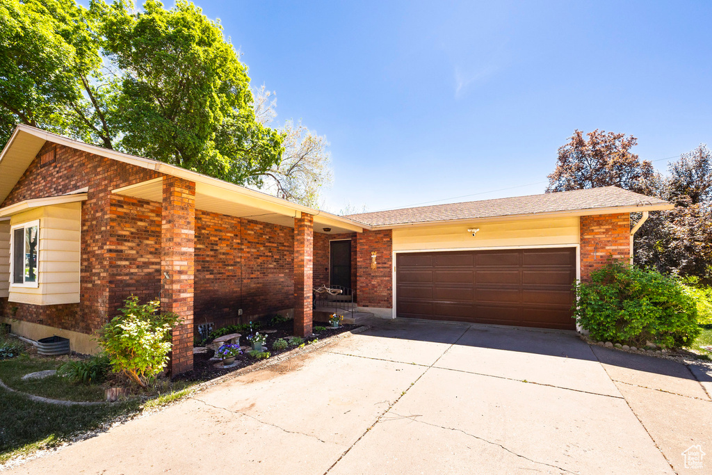 Single story home featuring concrete driveway, brick siding, and a garage
