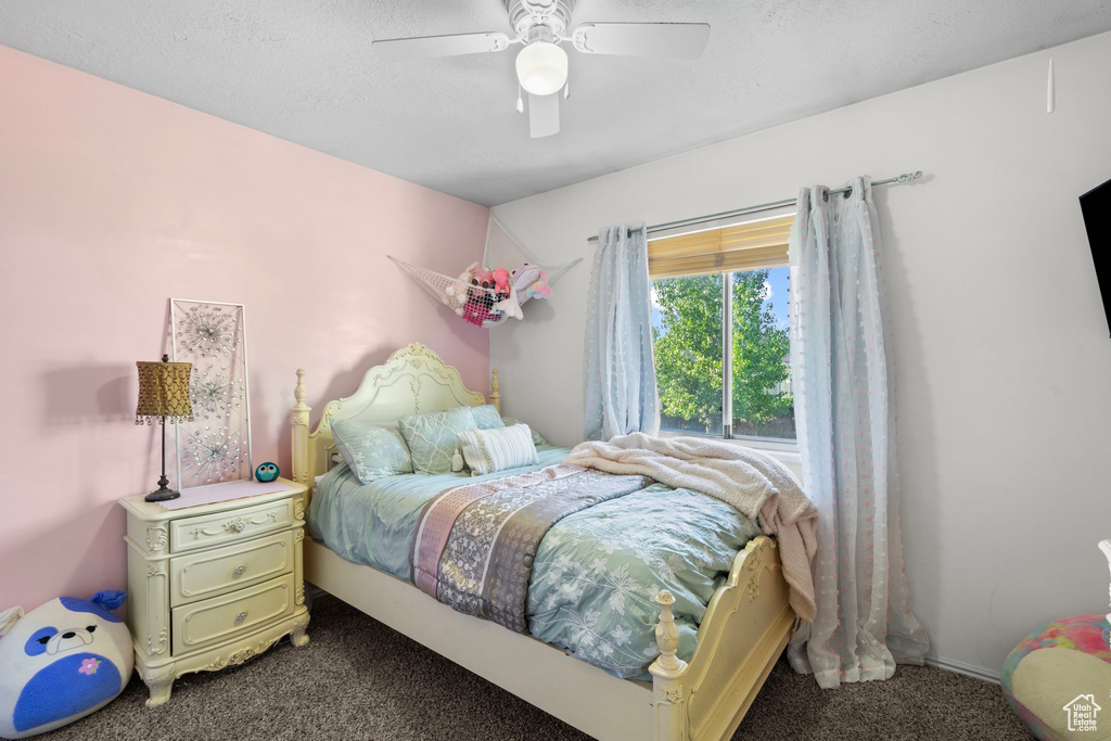 Bedroom with dark colored carpet and a ceiling fan